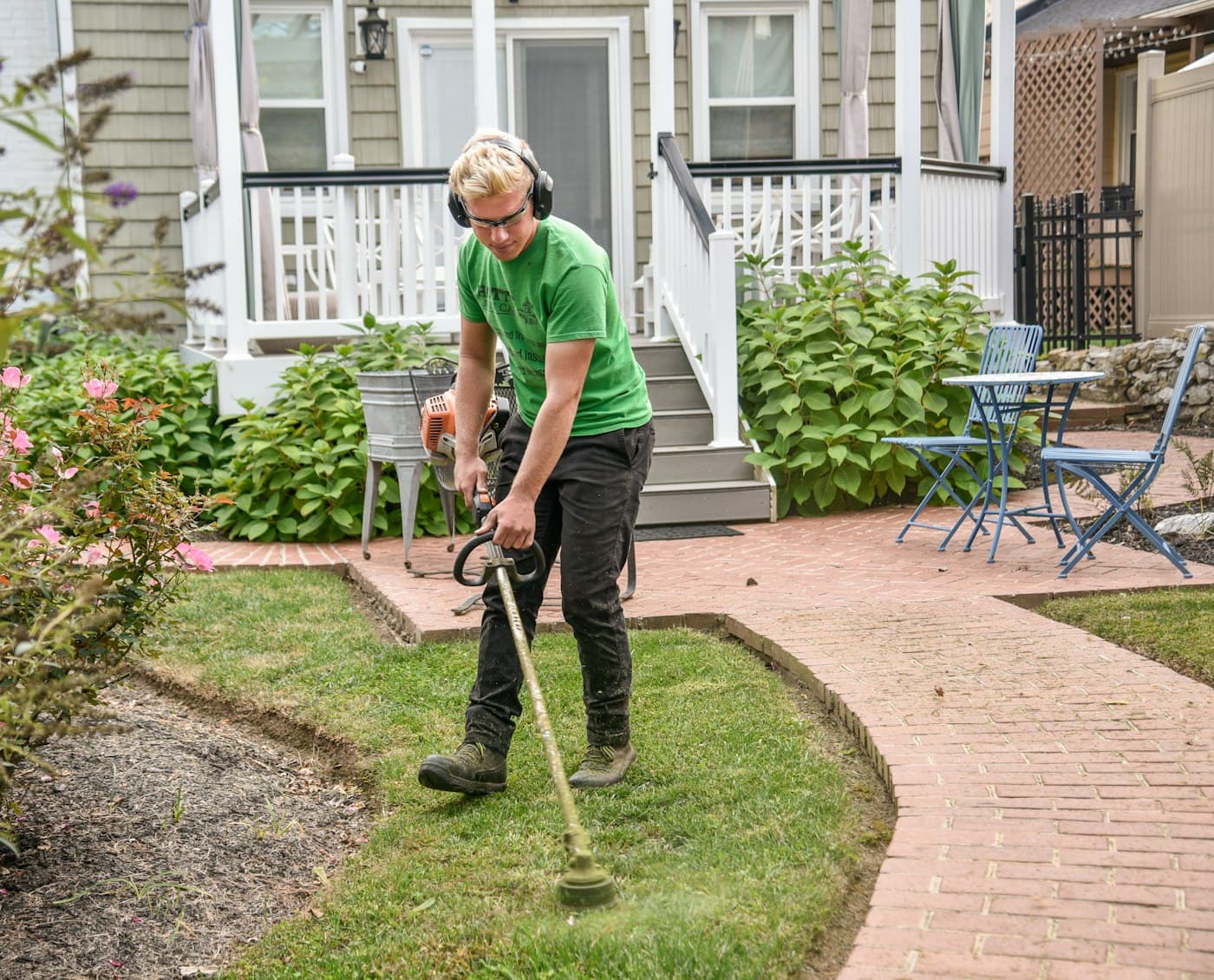 Gardener trimming a lawn edge as part of ASBDS Landscaping's maintenance work
